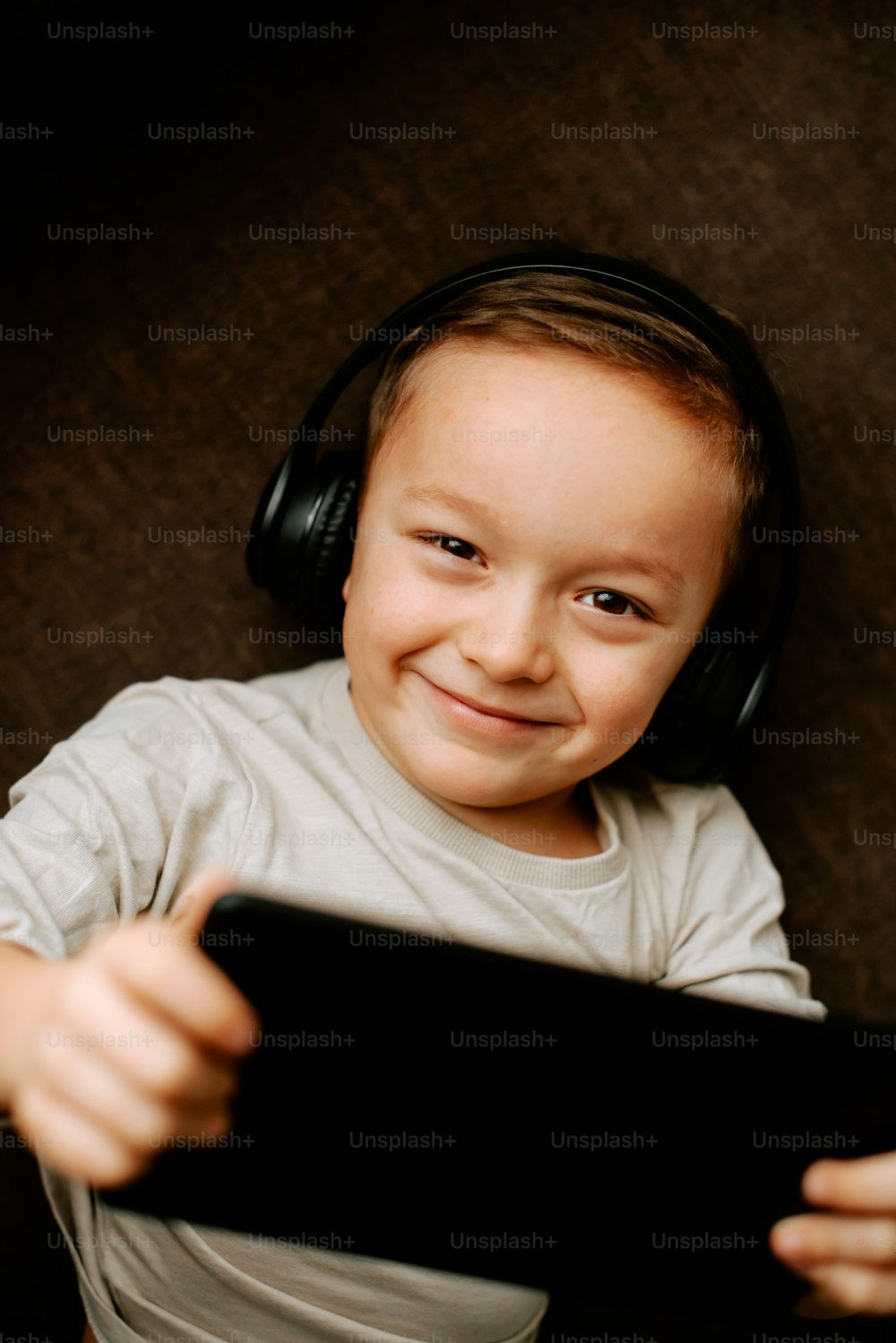 Ein kleiner Junge mit Kopfhörern und einem Tablet in der Hand