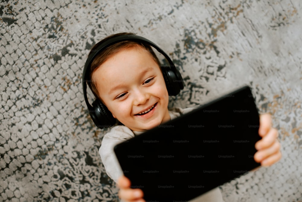 a little girl wearing headphones and holding a tablet