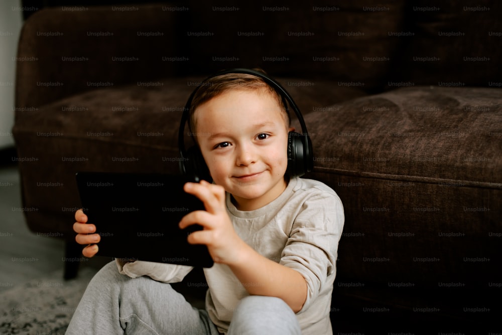 a little boy sitting on the floor with headphones on