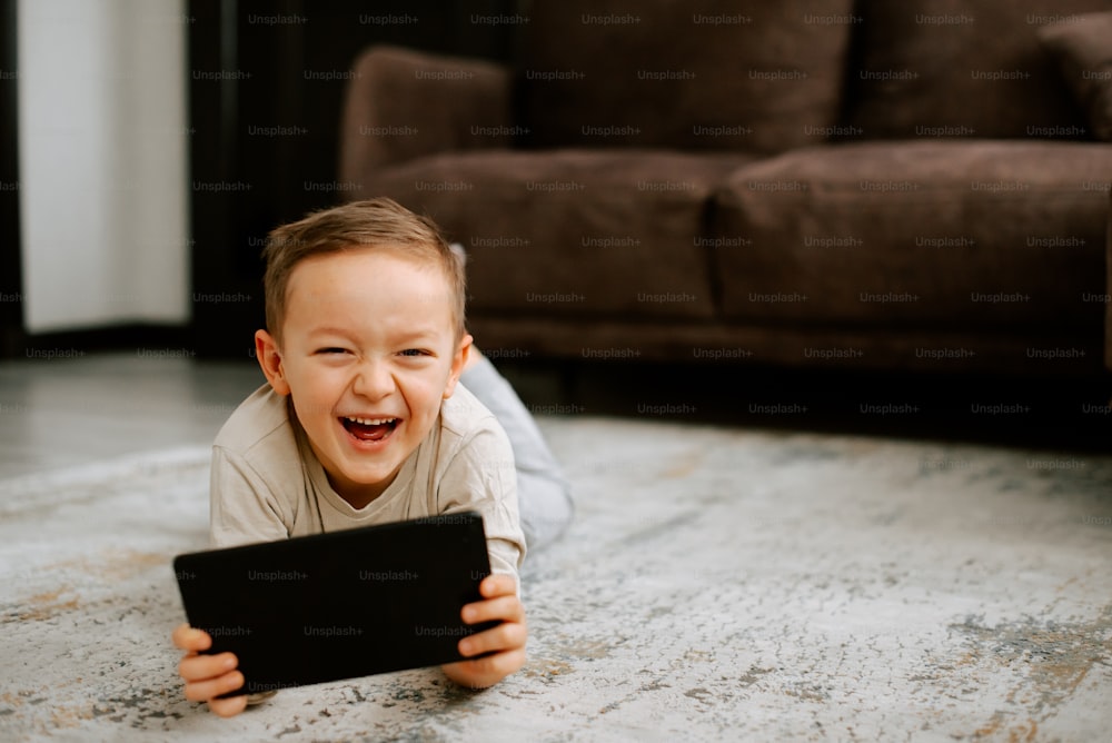 a little boy laying on the floor with a tablet