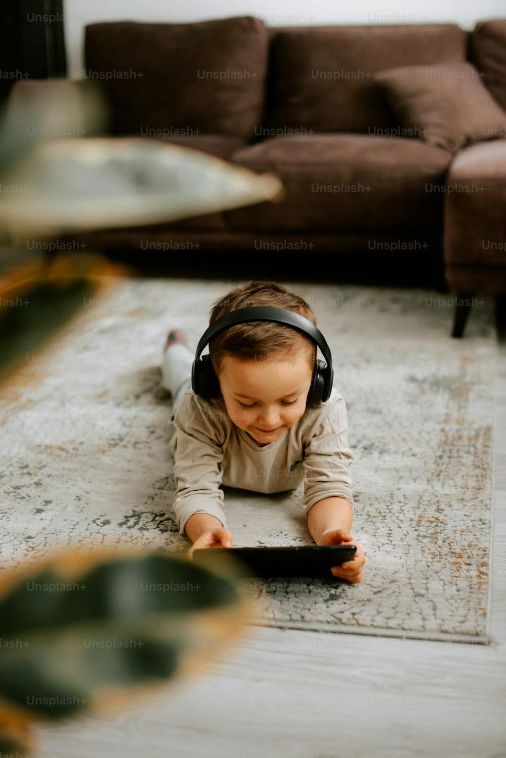 Ein kleines Mädchen liegt mit Kopfhörern auf dem Boden