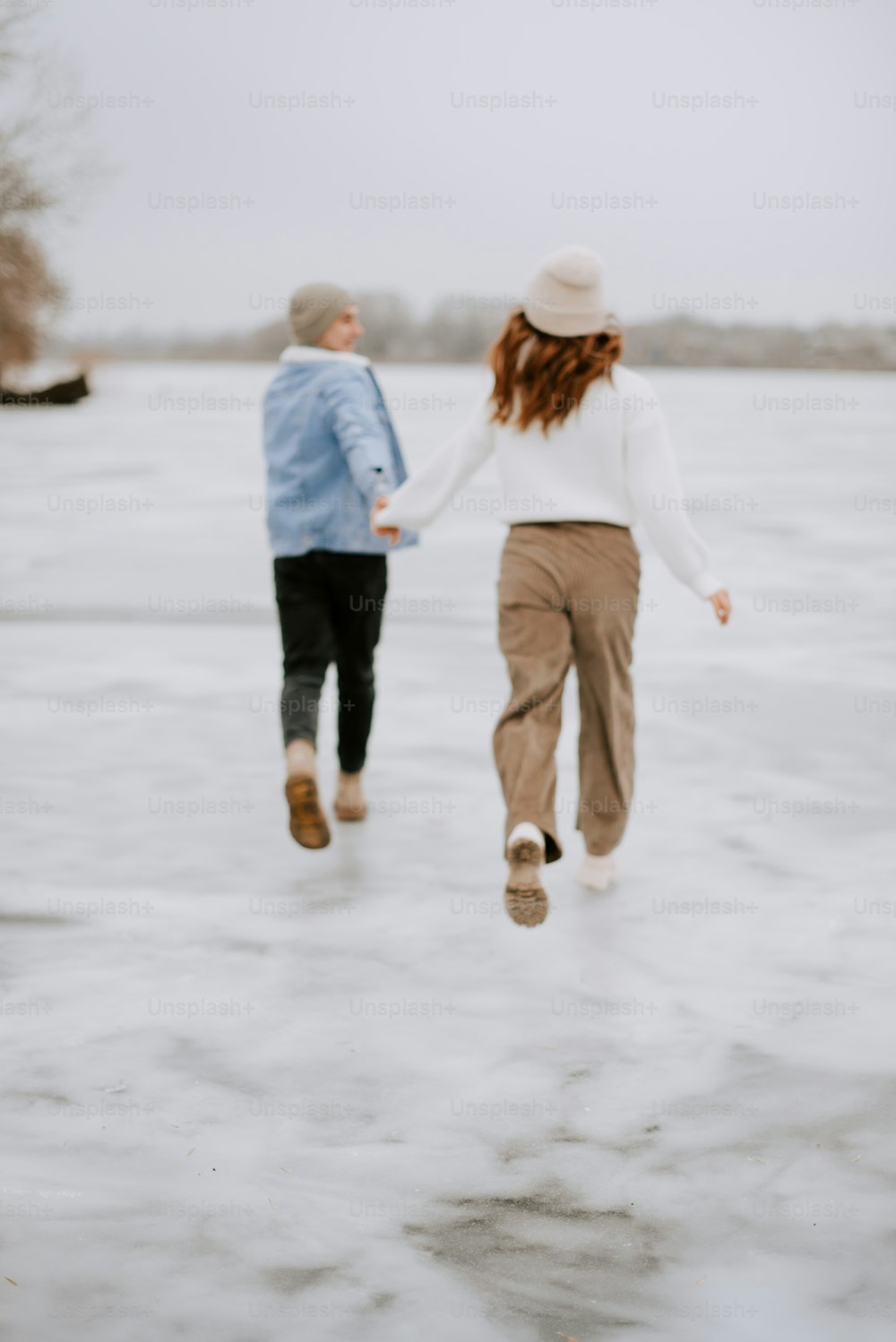 two people walking across a frozen lake holding hands