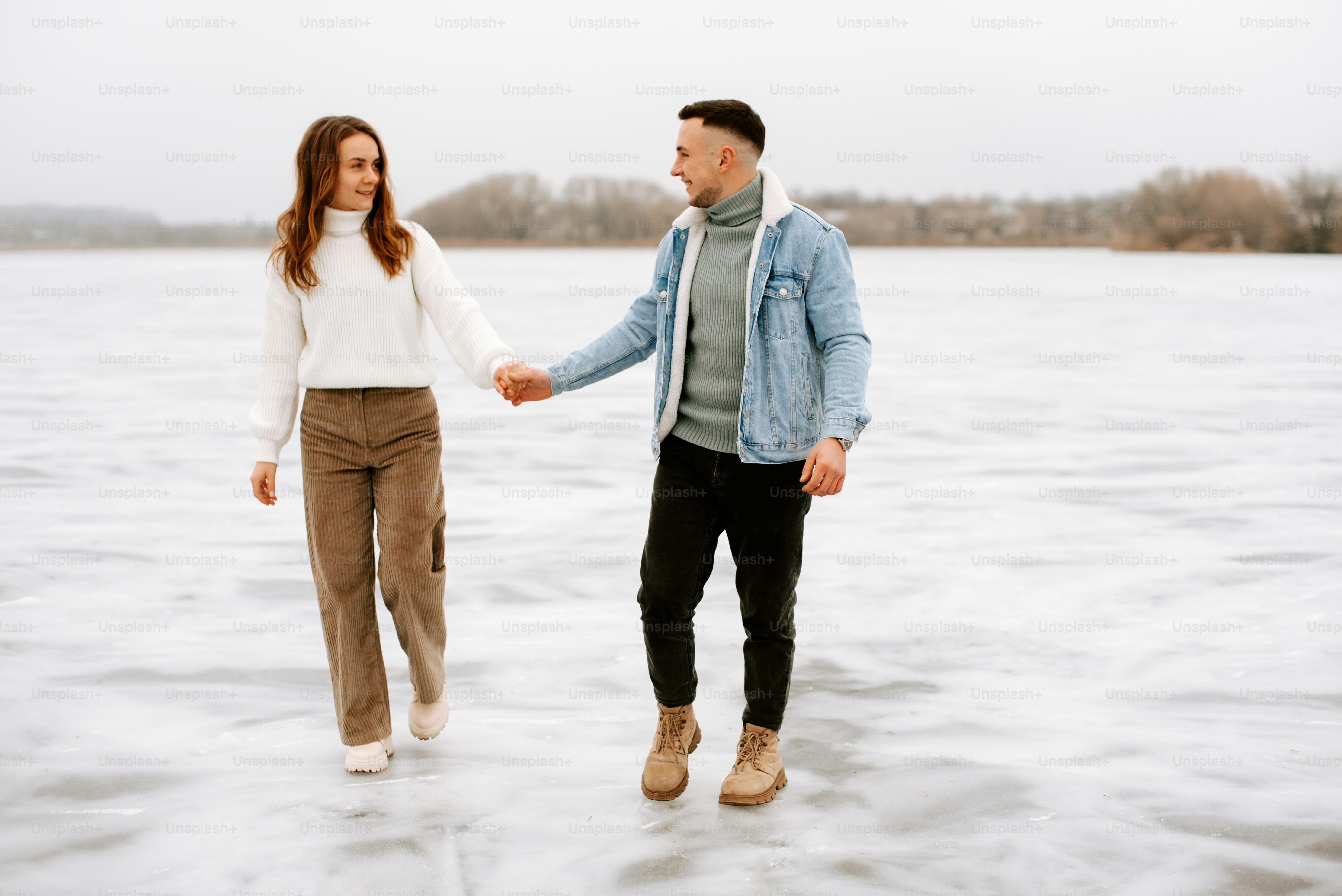 a man and a woman holding hands in the snow