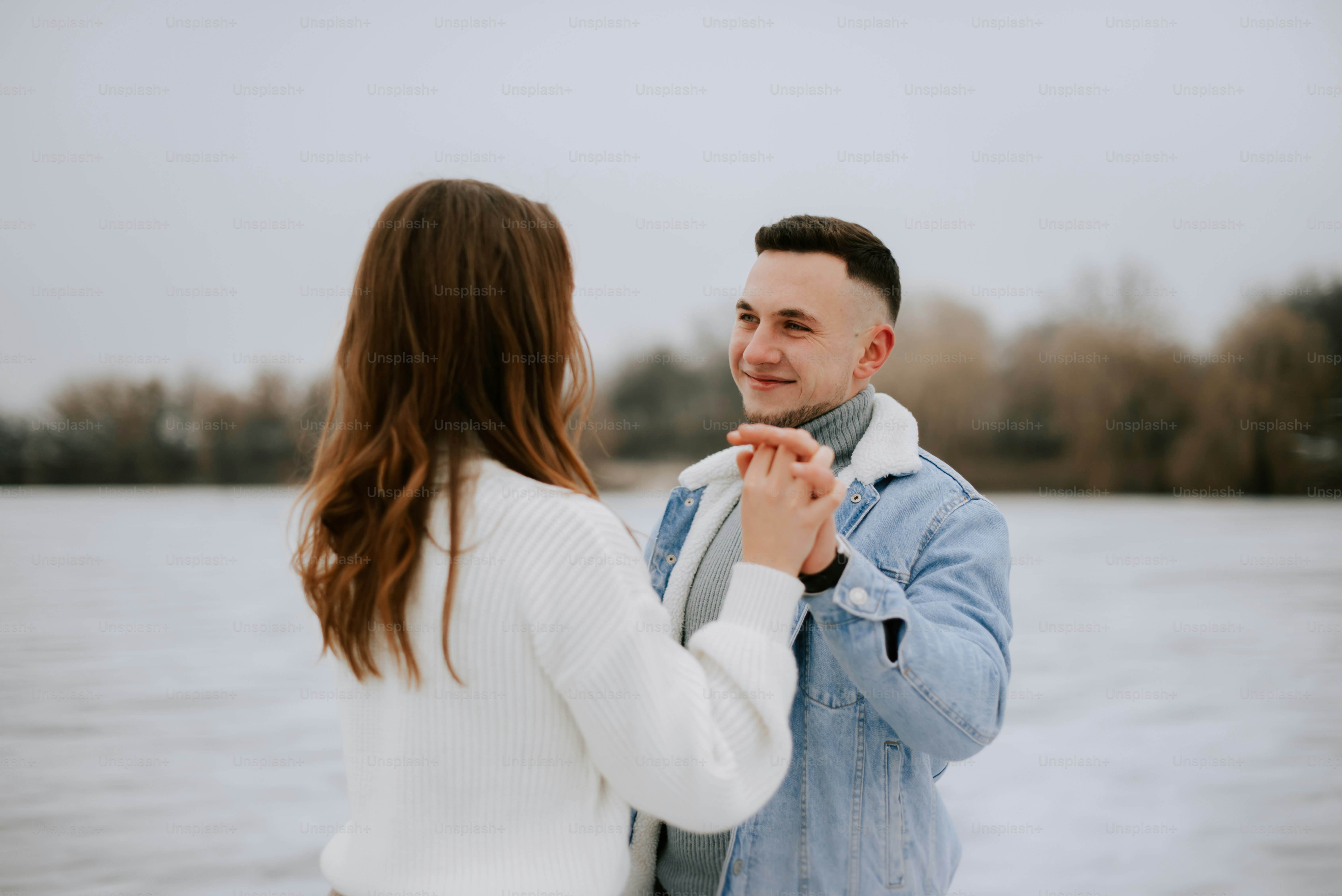 a man and woman standing next to each other in front of a body of water