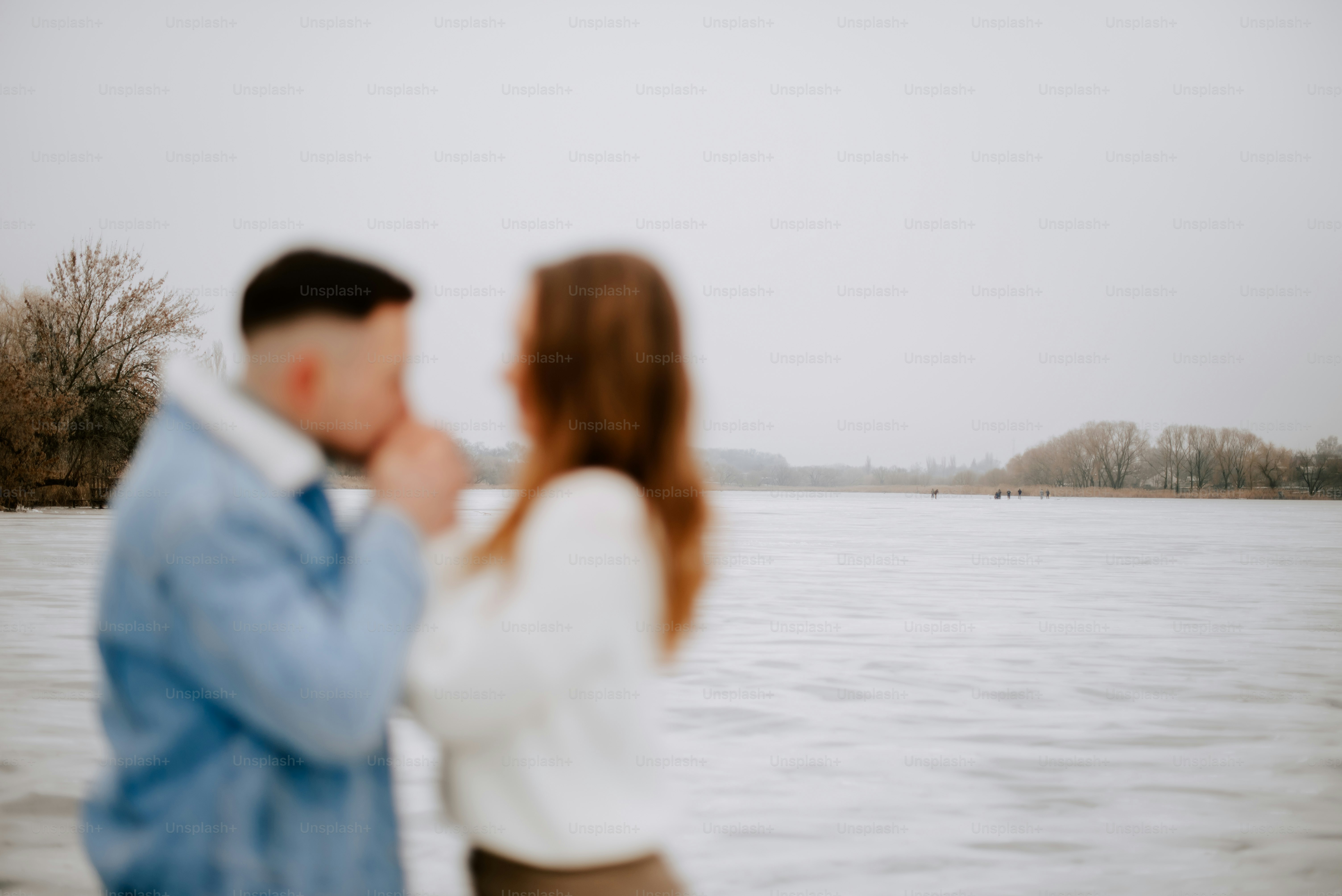a man and a woman standing in front of a body of water