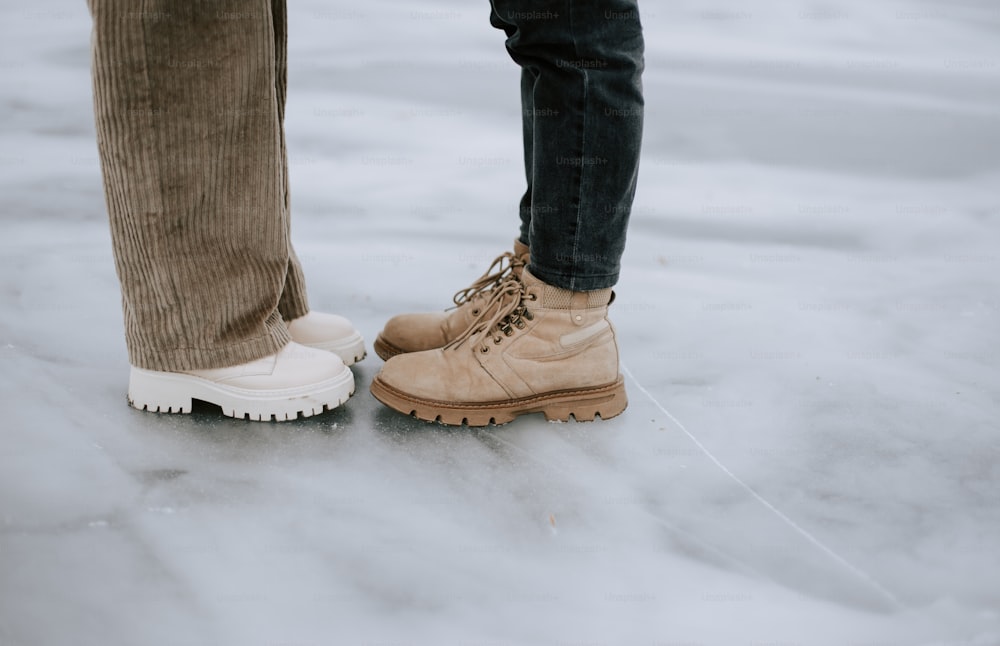 a pair of people standing on top of a snow covered ground