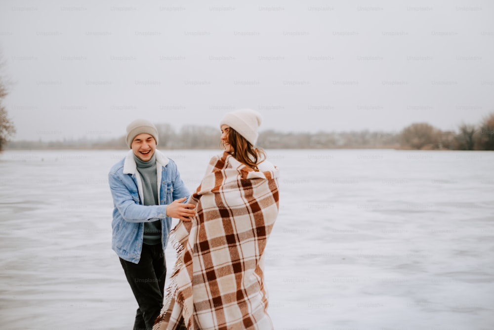 a man and a woman wrapped in a blanket by the water