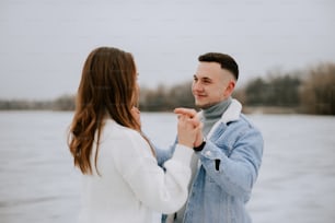 a man and a woman standing next to each other in front of a body of