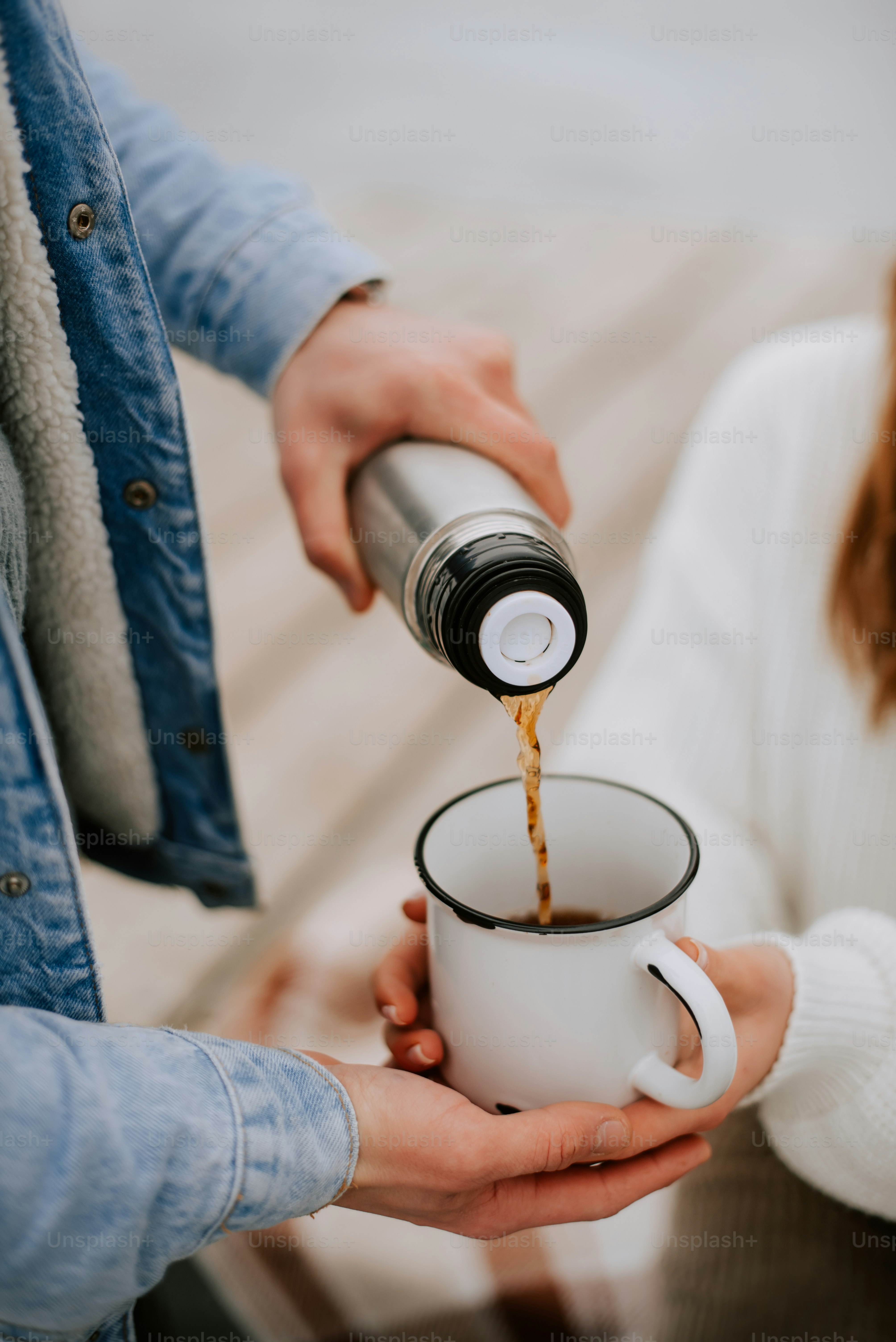 a person pouring a cup of coffee into another person's hand