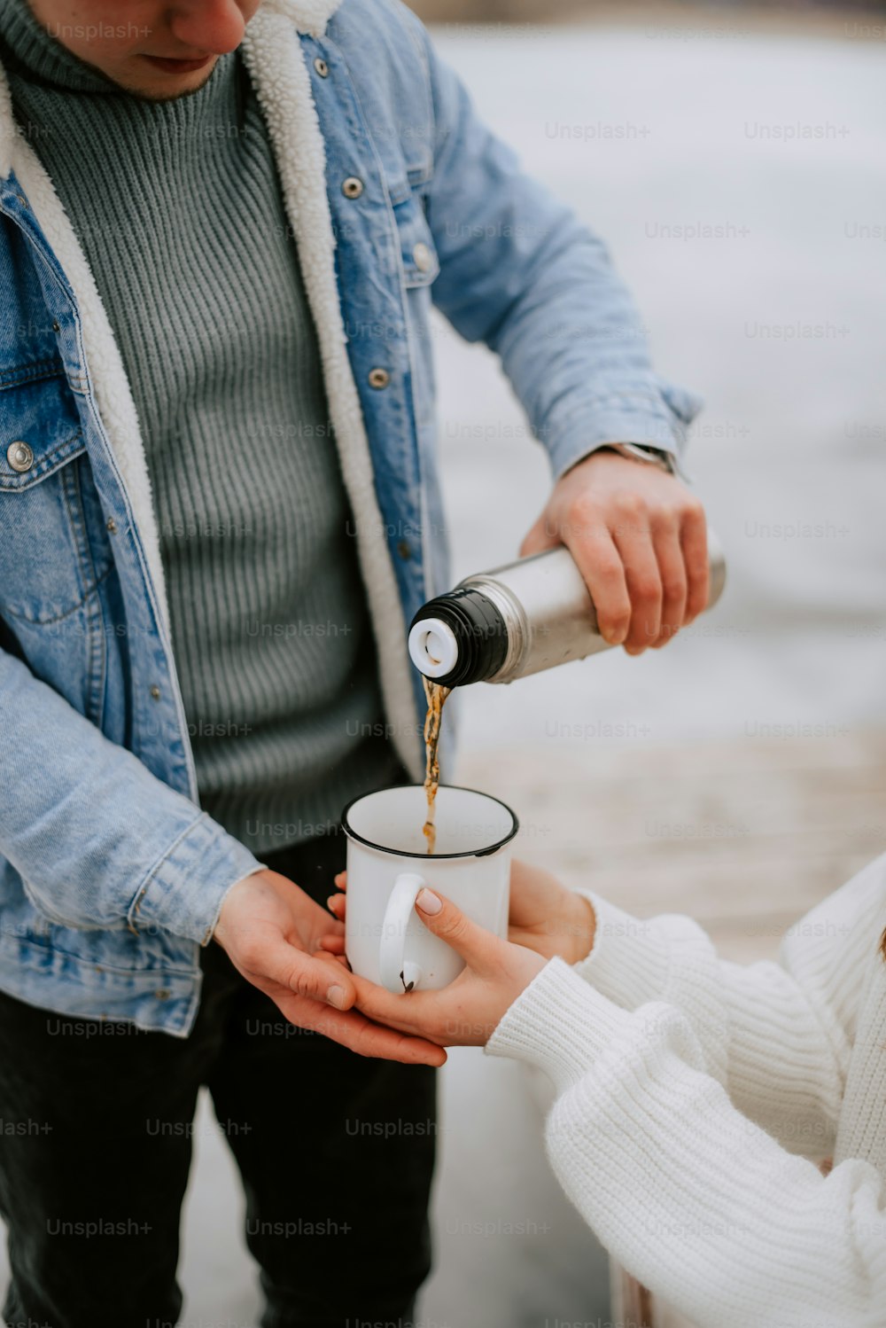 a man pouring something into a cup while a woman looks on