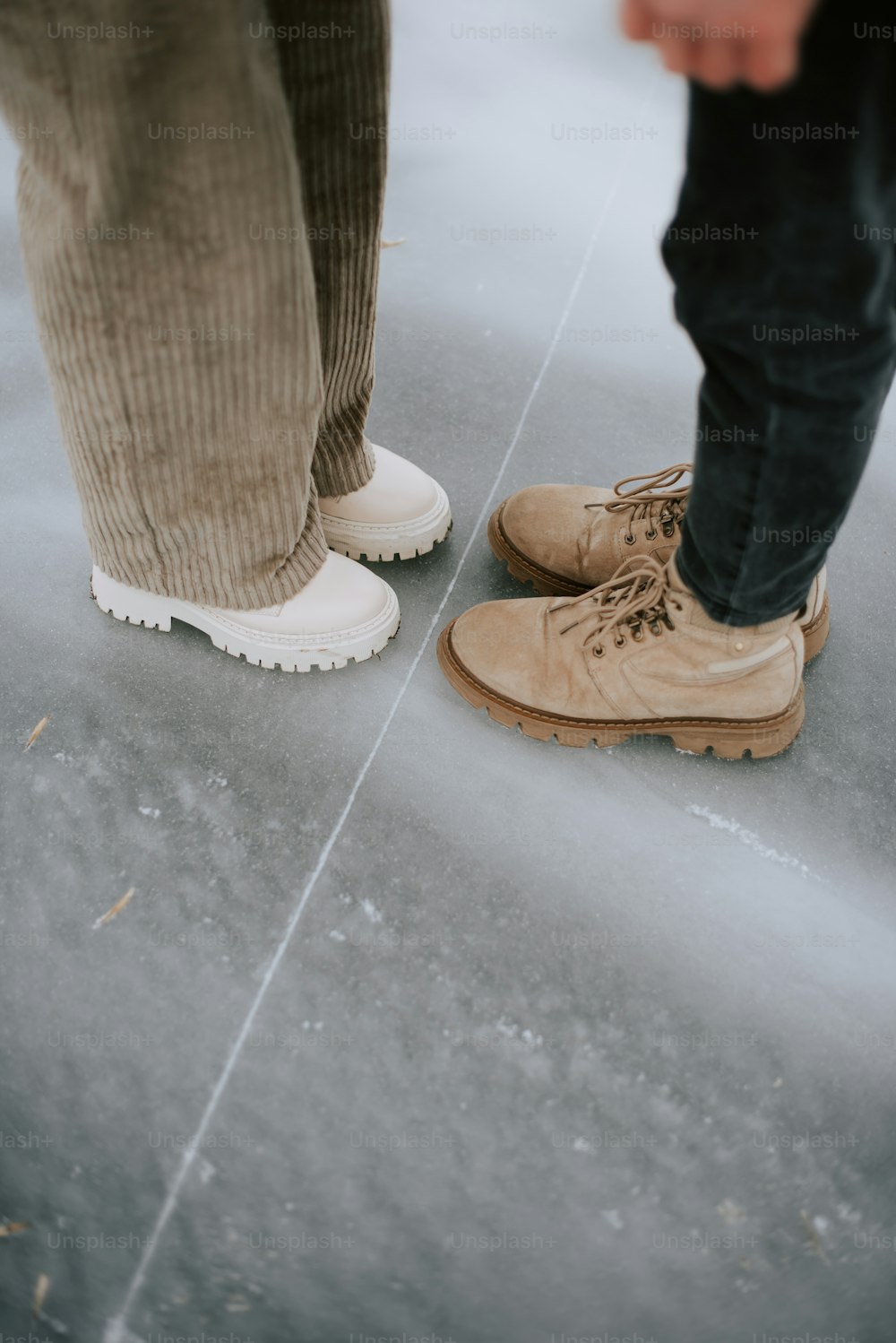 eine Person, die neben einer anderen Person steht und braune Schuhe trägt