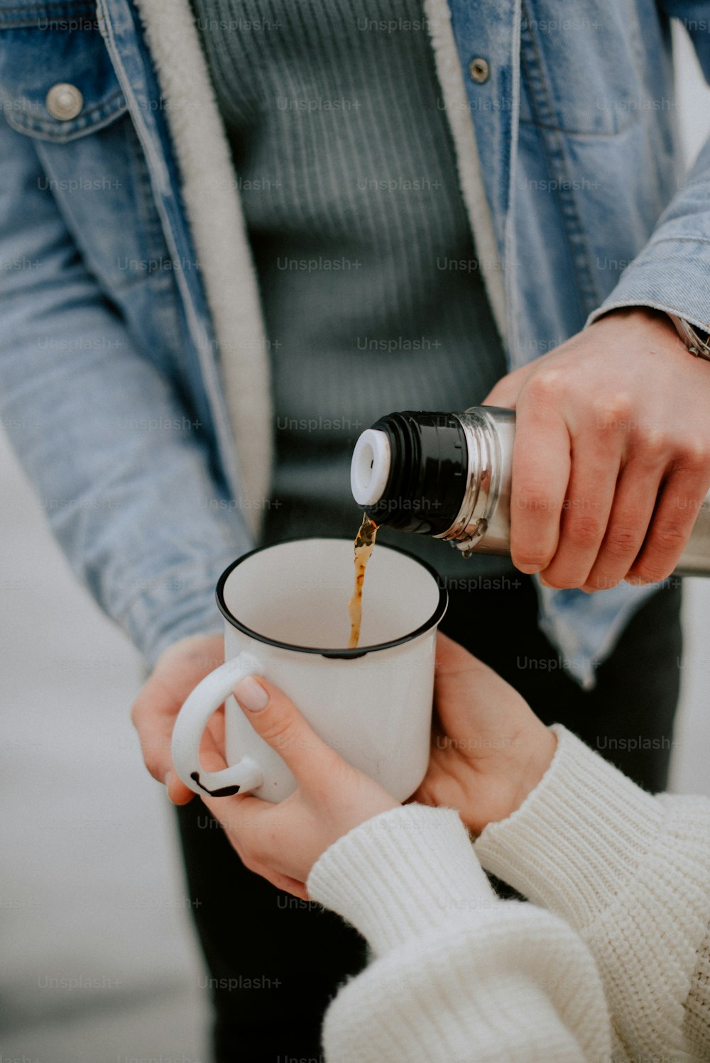 a person pouring a cup of coffee into another person's hand