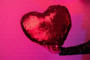 a woman holding a heart shaped sequin pillow