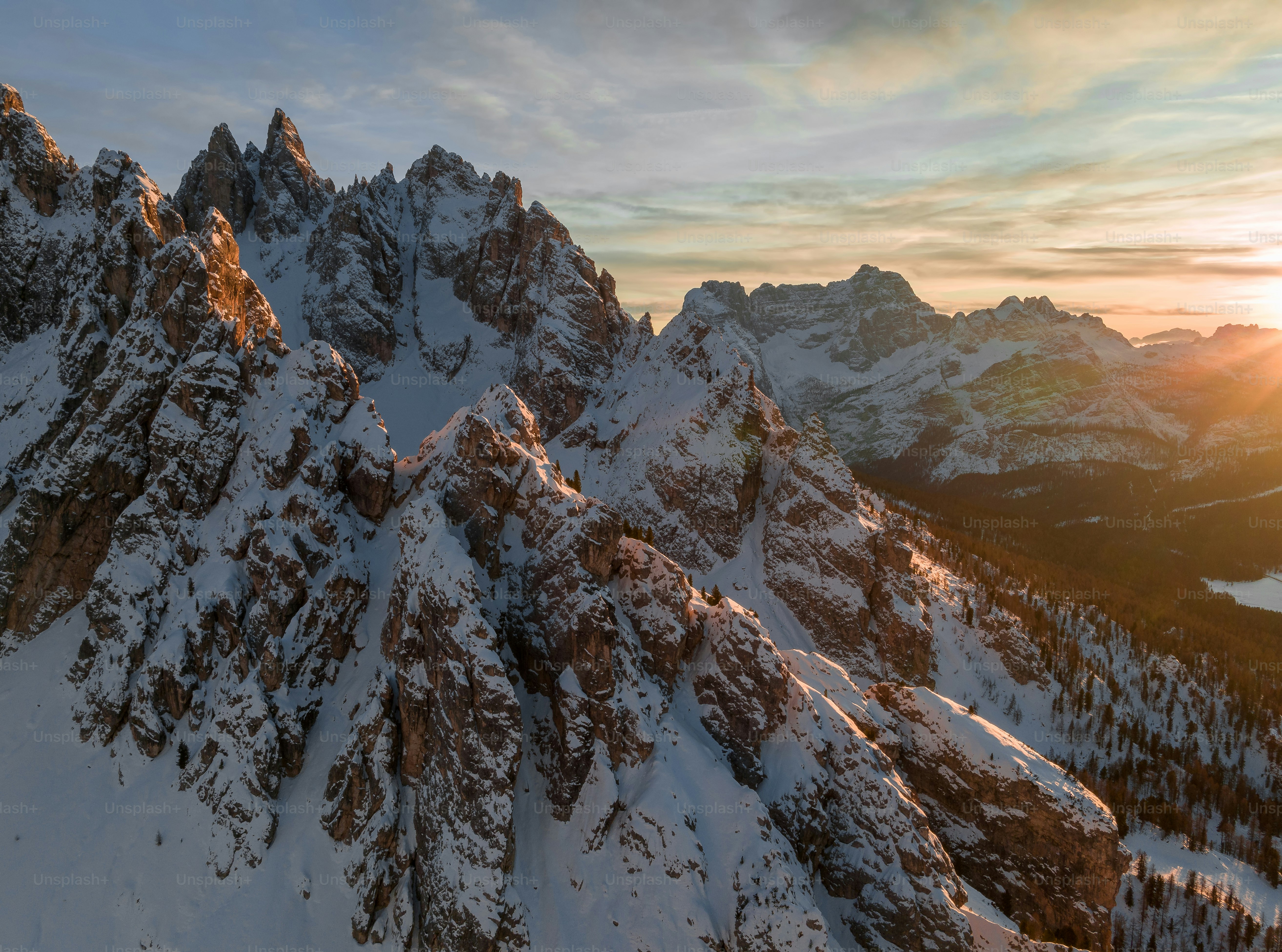 A snow covered mountain range with trees in the foreground photo ...