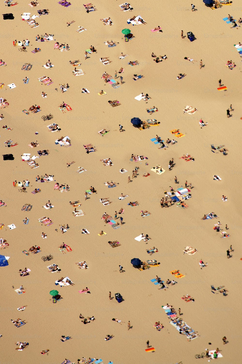 um grande grupo de pessoas deitadas em cima de uma praia de areia