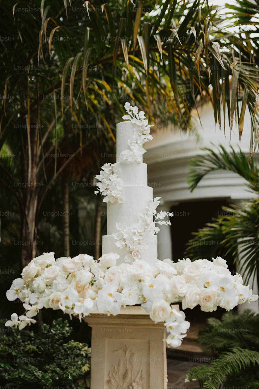 eine Hochzeitstorte mit weißen Blumen auf einem Podest
