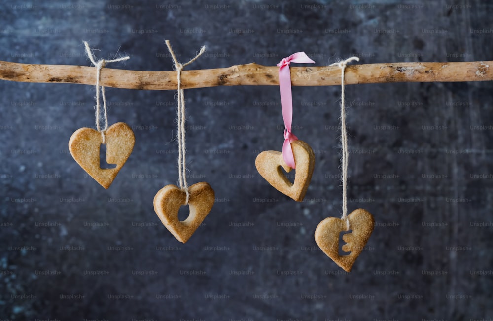 three heart shaped cookies hanging from a twig