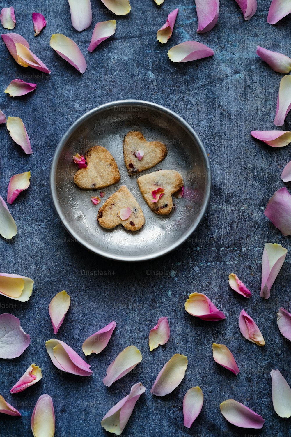um prato de biscoitos em forma de coração cercado por pétalas