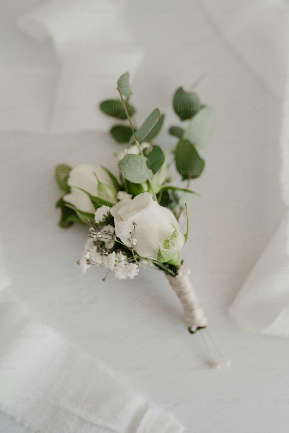 a boutonniere with white flowers and green leaves