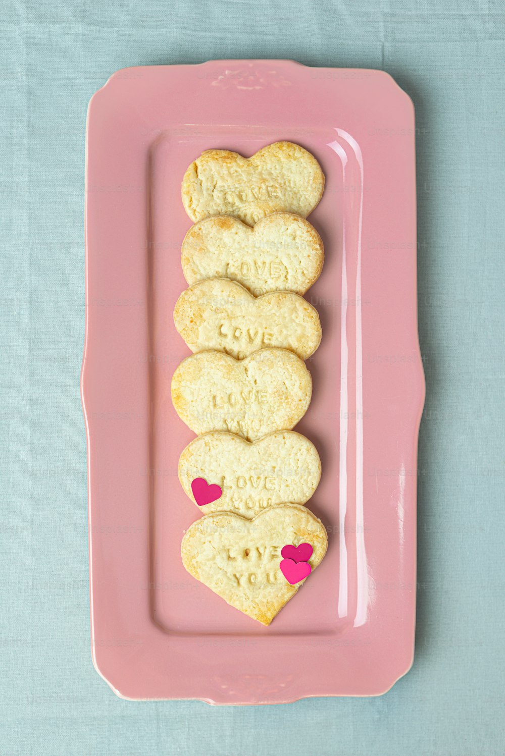 하트 모양의 쿠키를 얹은 분홍색 접시