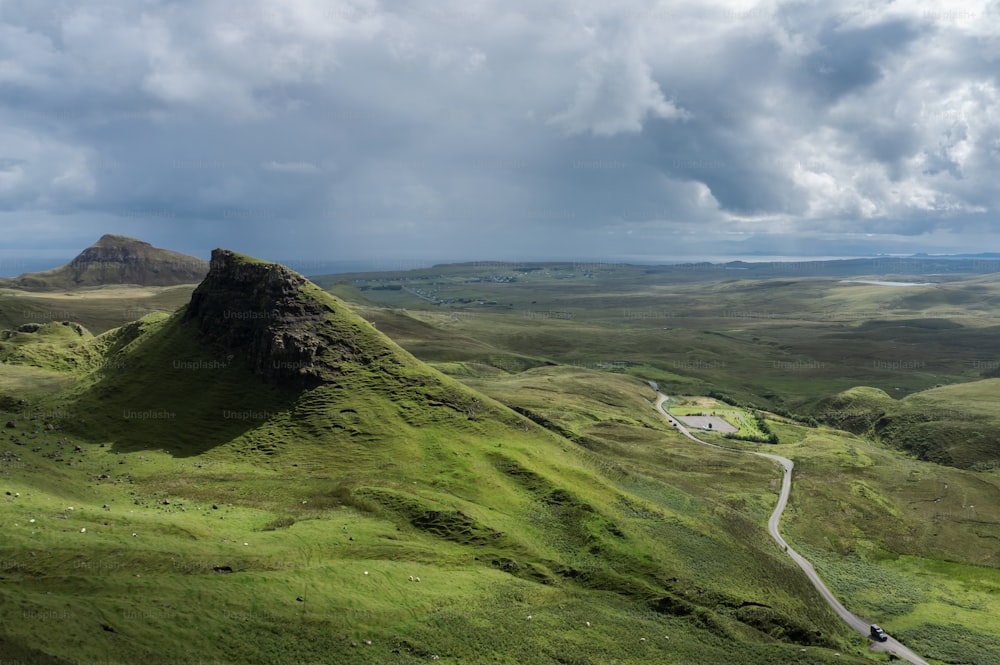 a green mountain with a winding road in the middle of it