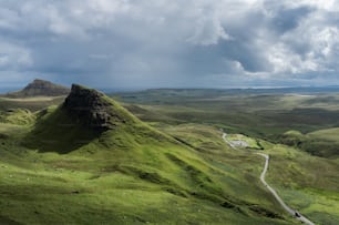 a green mountain with a winding road in the middle of it