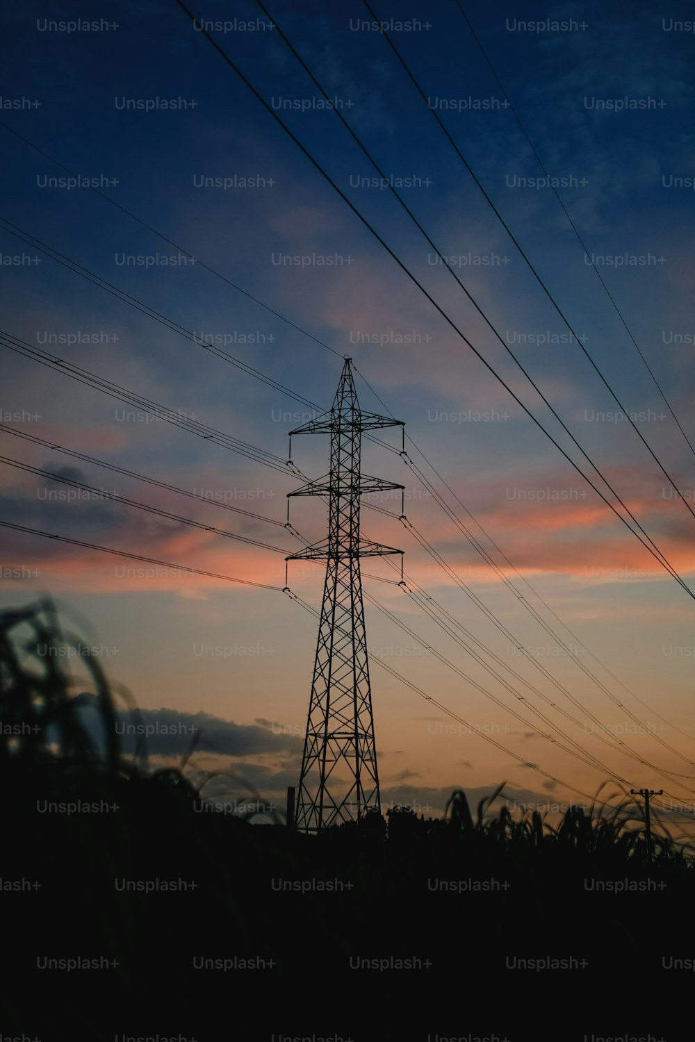 Una linea elettrica ad alta tensione con un tramonto sullo sfondo