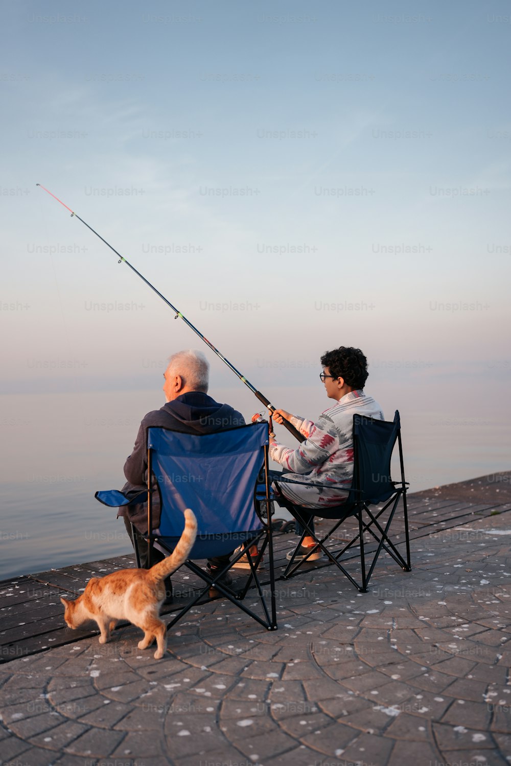 a man and a woman sitting in lawn chairs fishing