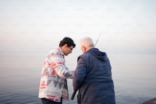 a couple of men standing next to each other near a body of water