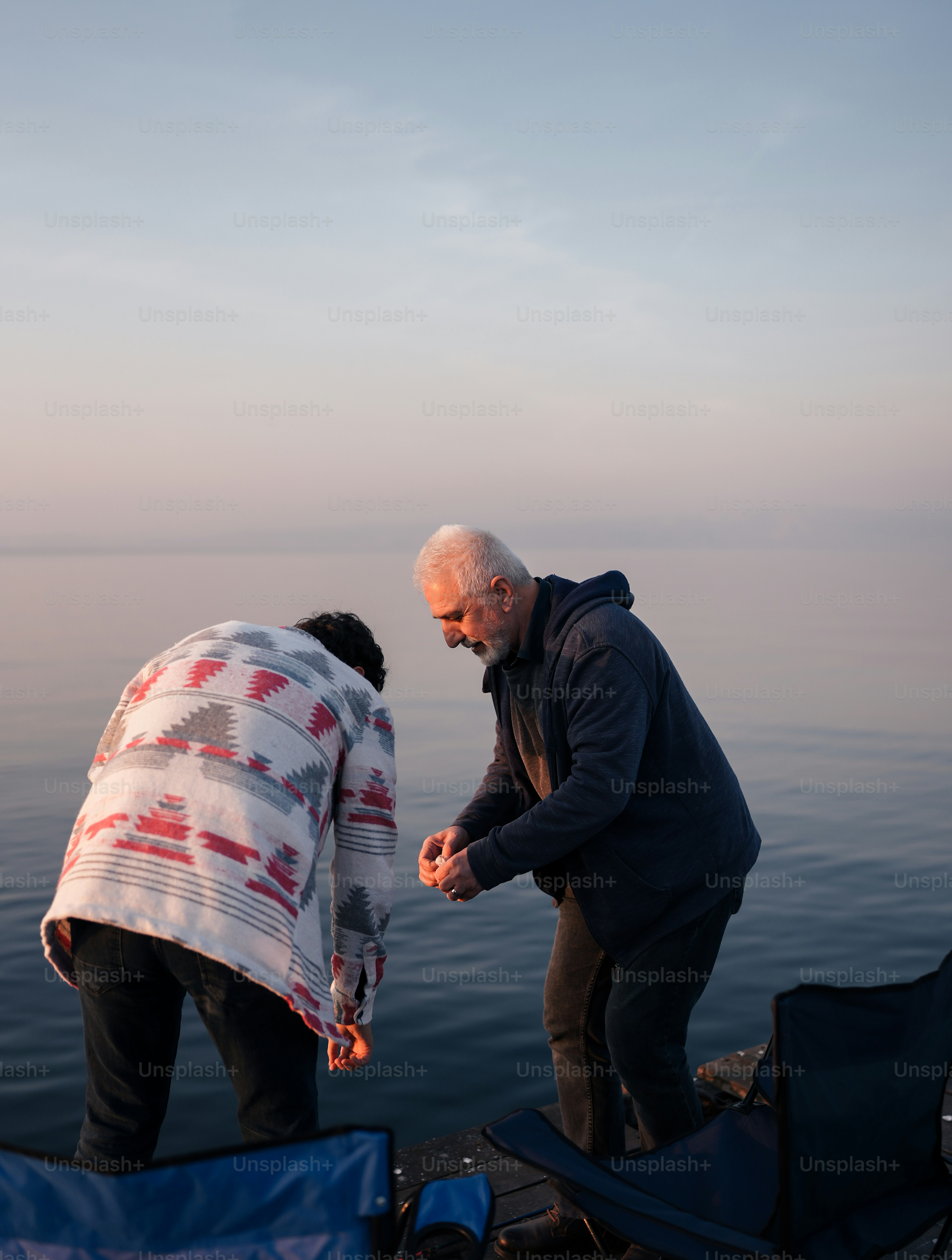 a couple of men standing next to a body of water