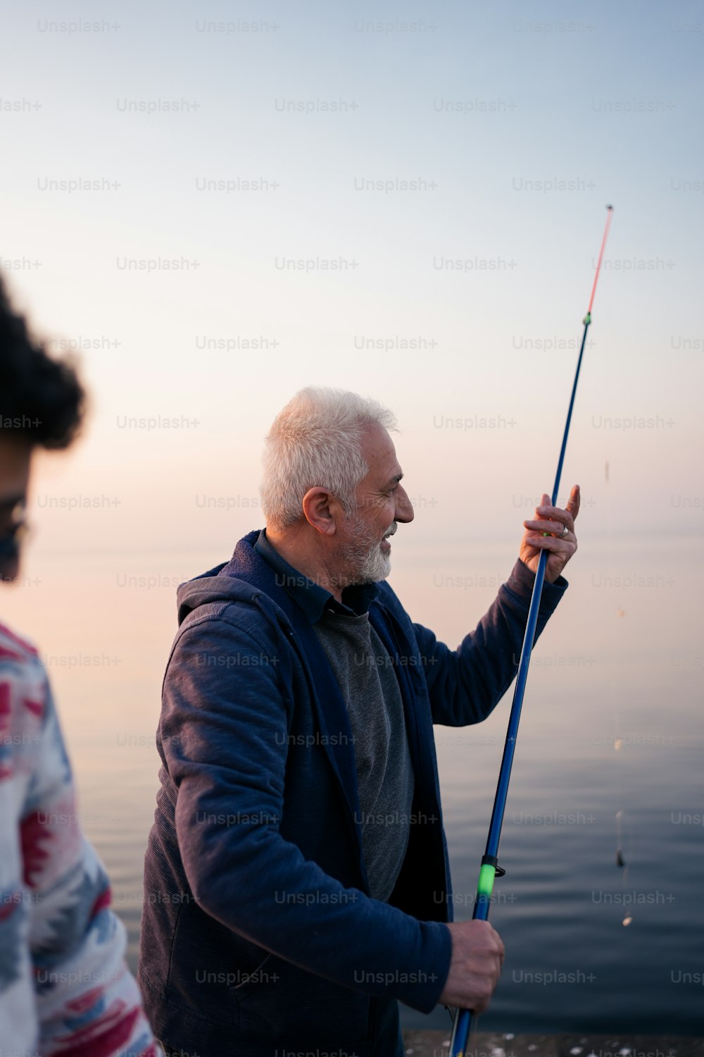a man holding a fishing pole while standing next to another man
