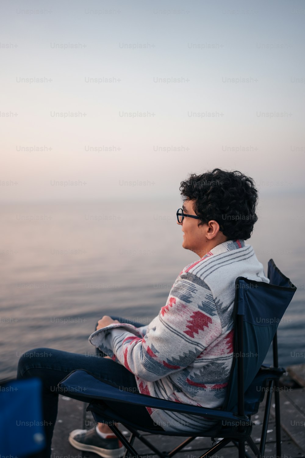 a man sitting in a chair looking out at the water