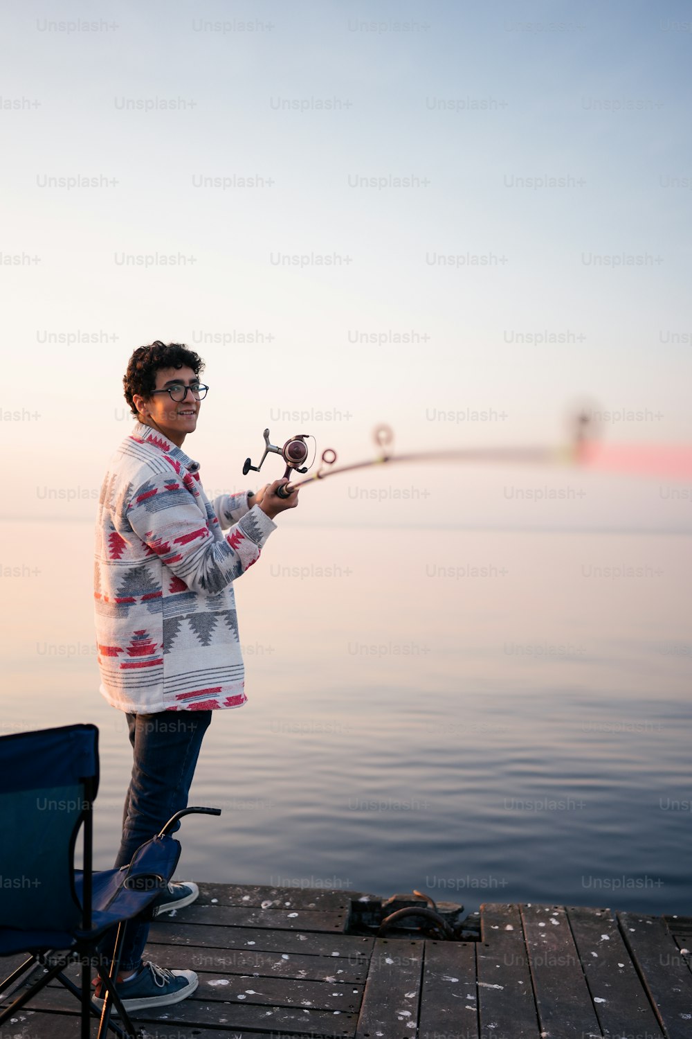 a man standing on a dock holding a fishing rod