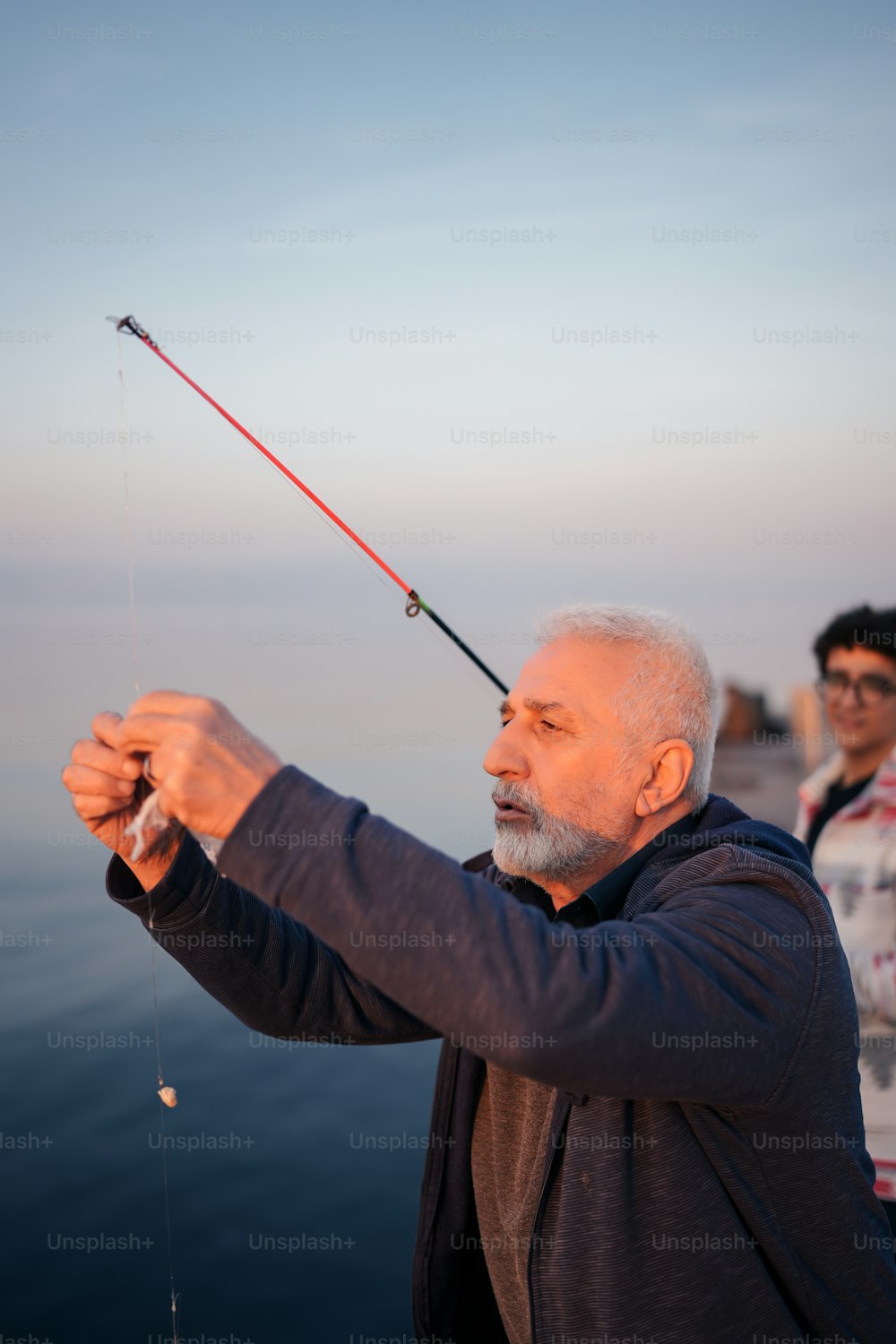 a man holding a fishing rod while standing next to a body of water