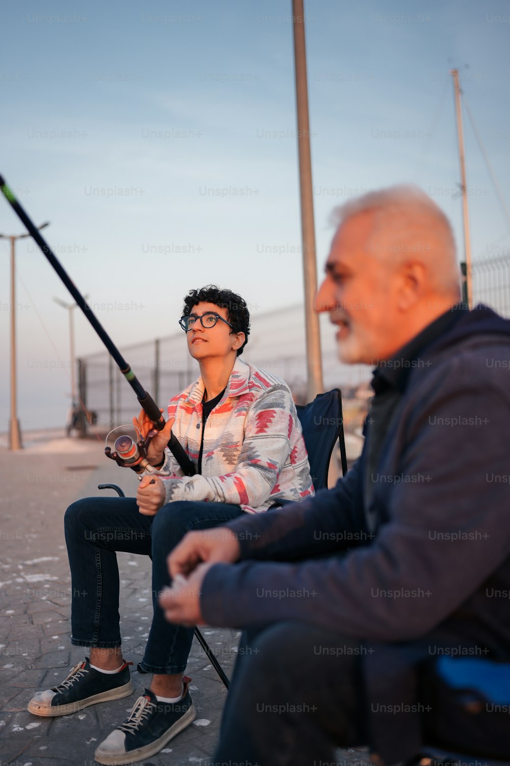 a man sitting next to a woman holding a fishing pole