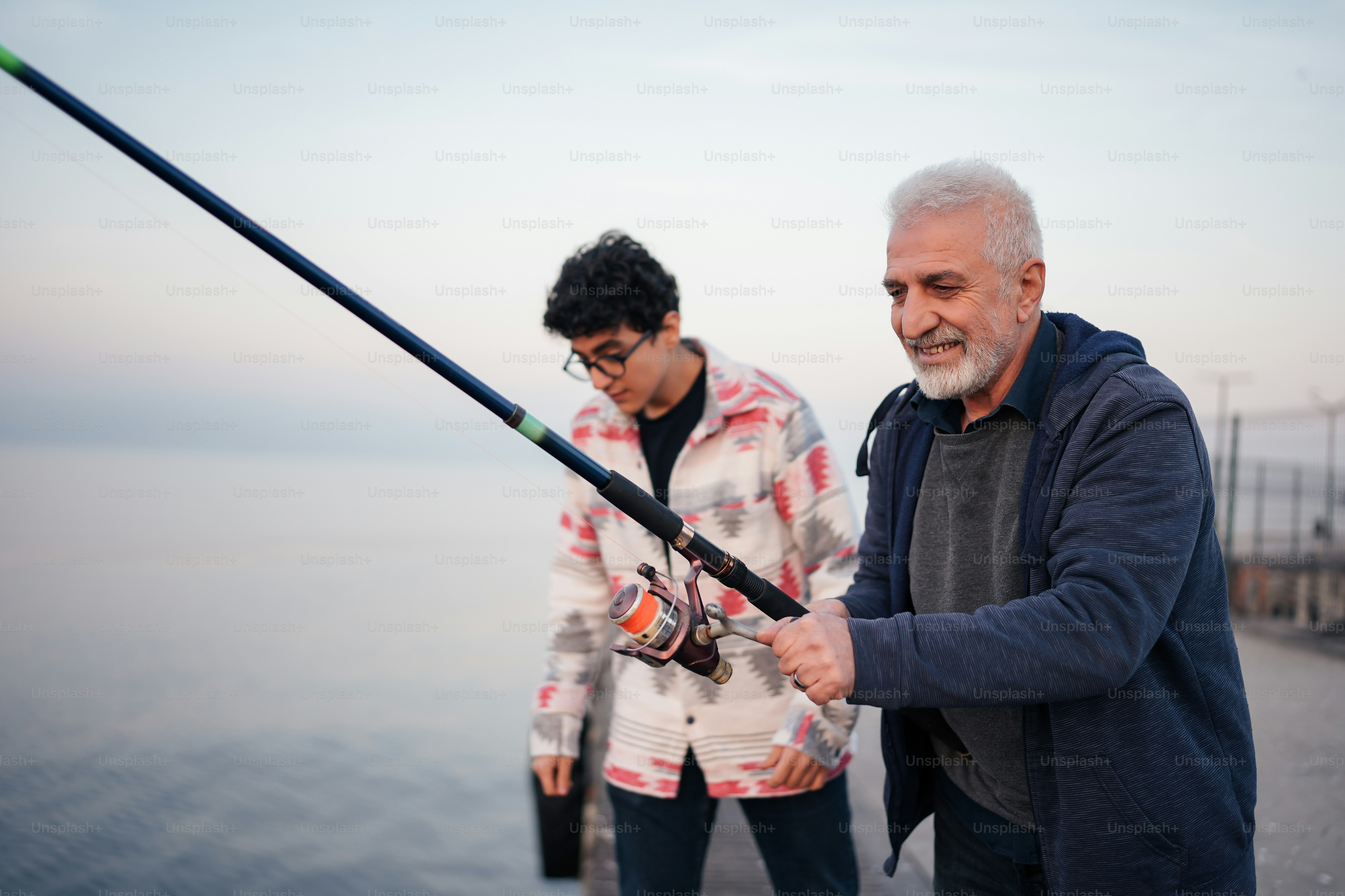 a man holding a fishing rod next to another man