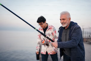 a man holding a fishing rod next to another man