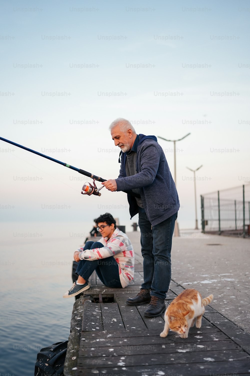 桟橋で釣りをする男と猫