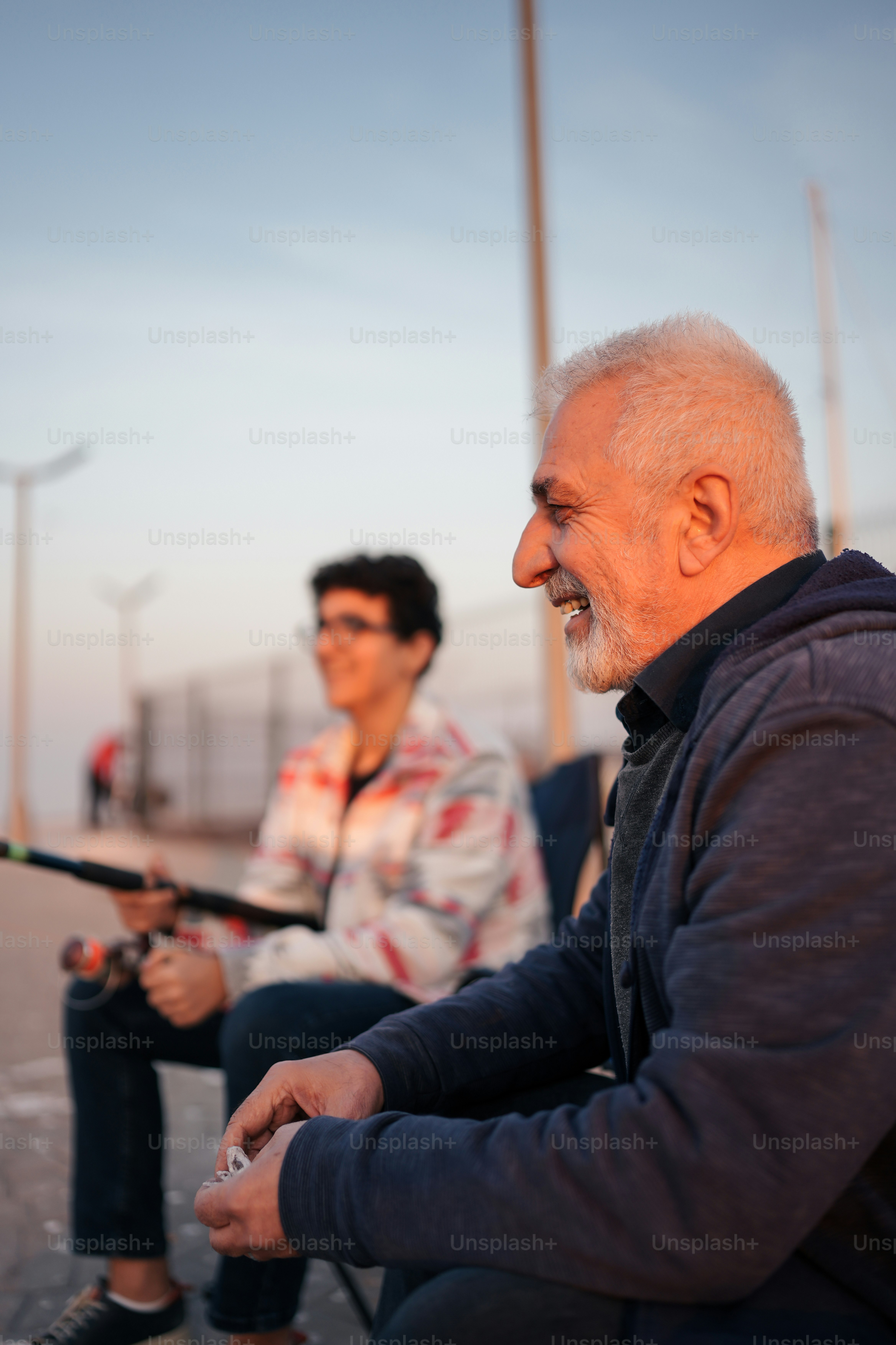 a man sitting next to another man holding a fishing pole