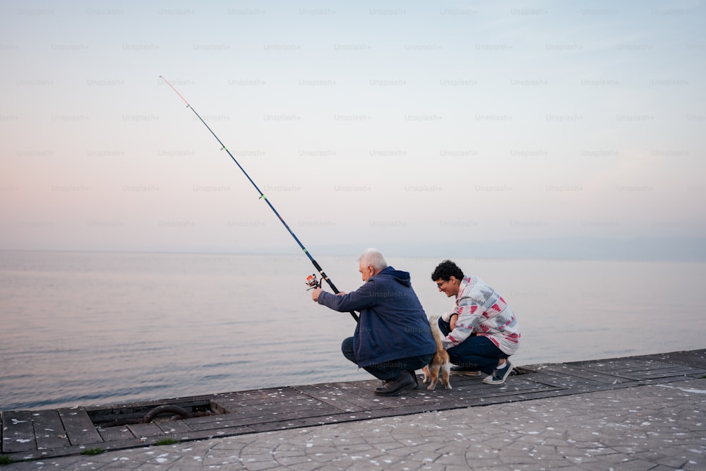 Un hombre arrodillado junto a una mujer que sostiene una caña de pescar