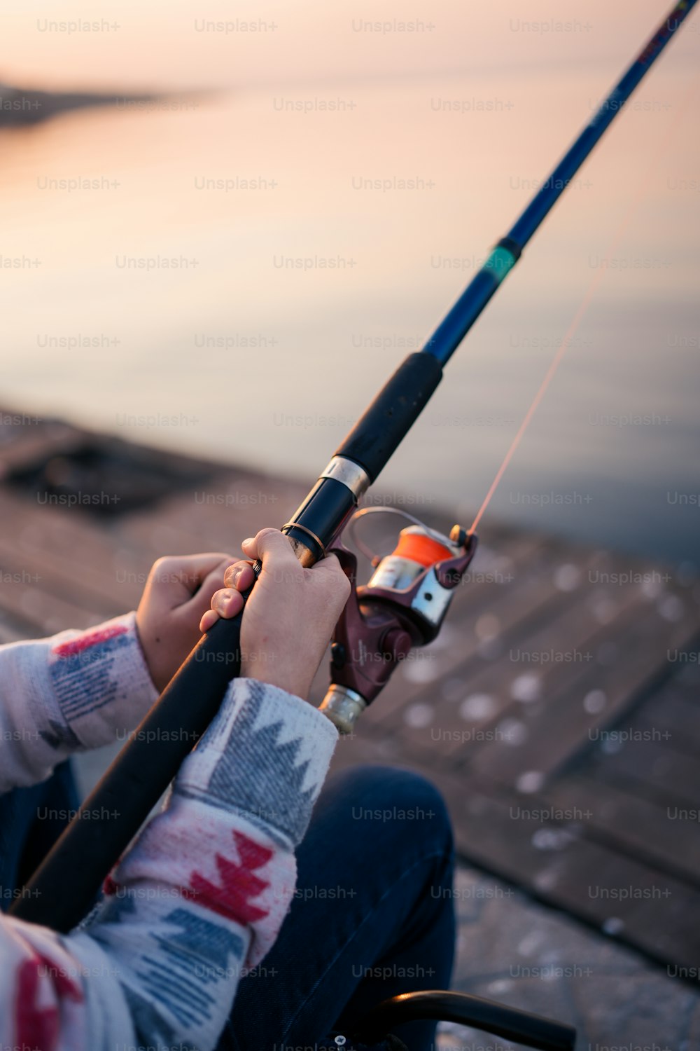 A person sitting on a dock holding a fishing pole photo – Fishing
