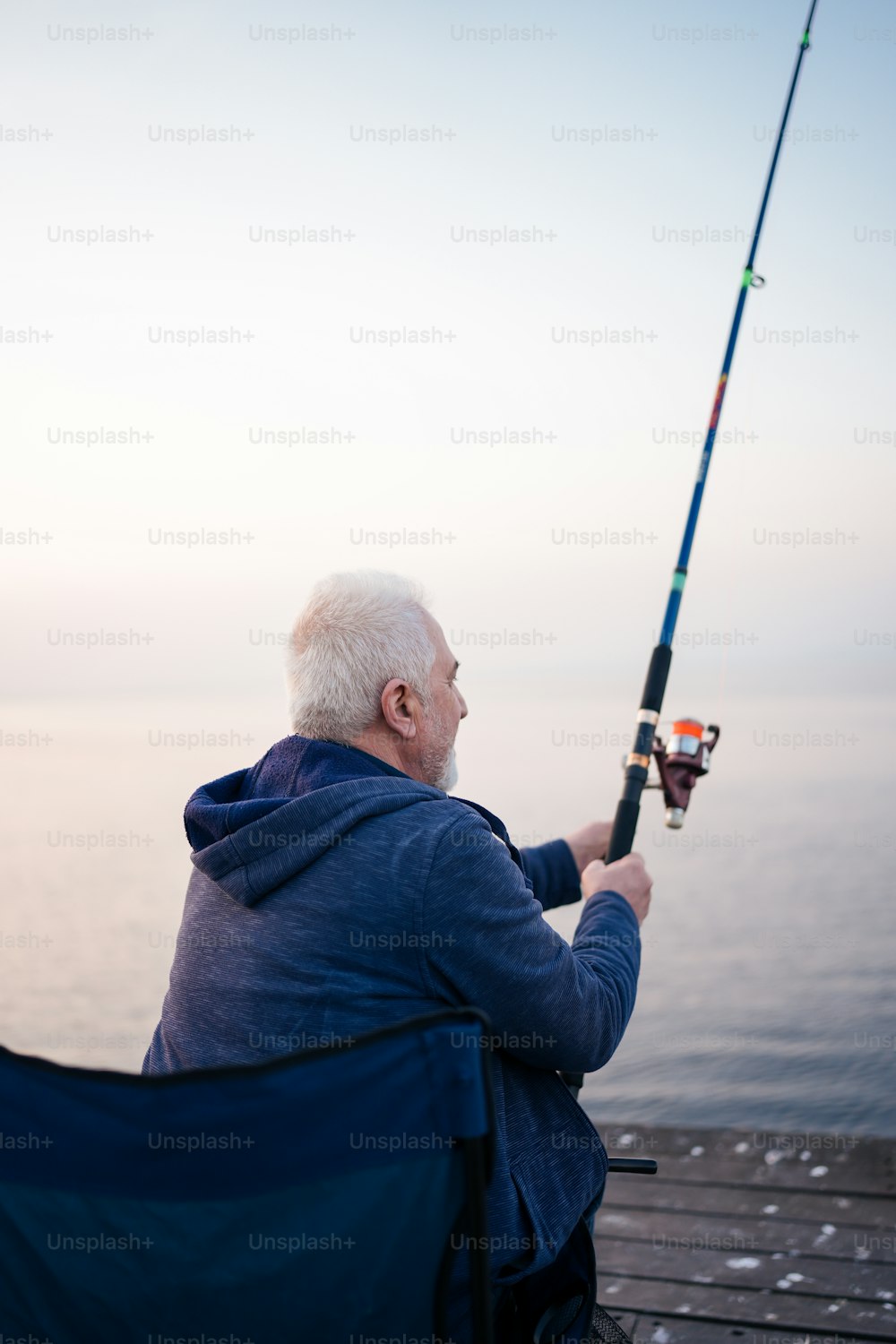 a man sitting on a bench while holding a fishing pole