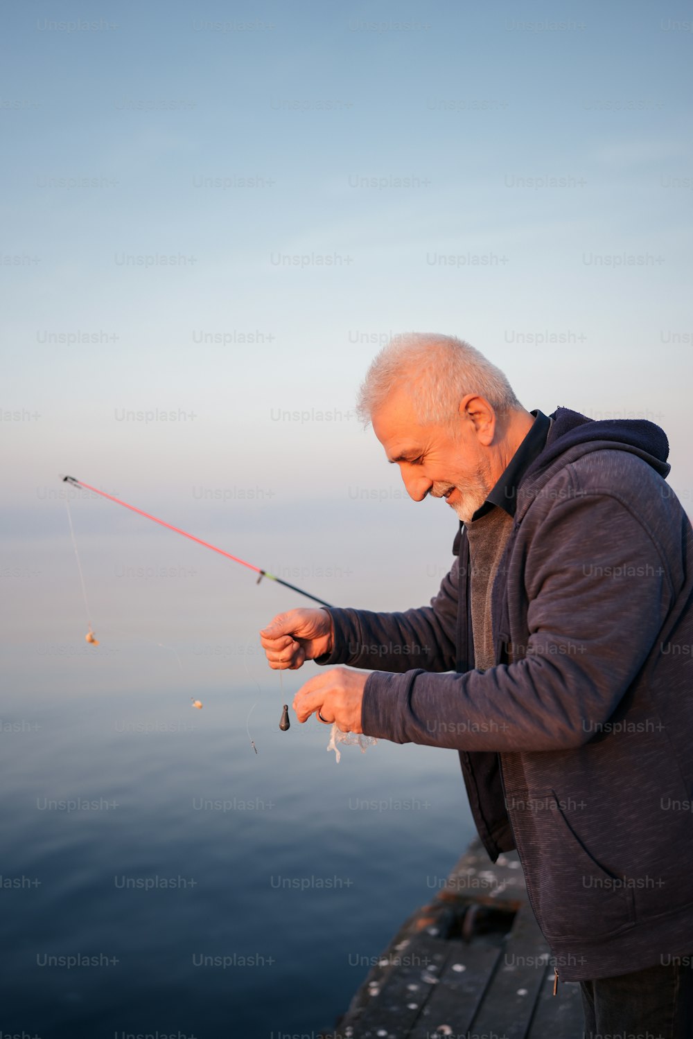 Un uomo in piedi su un molo che tiene una canna da pesca