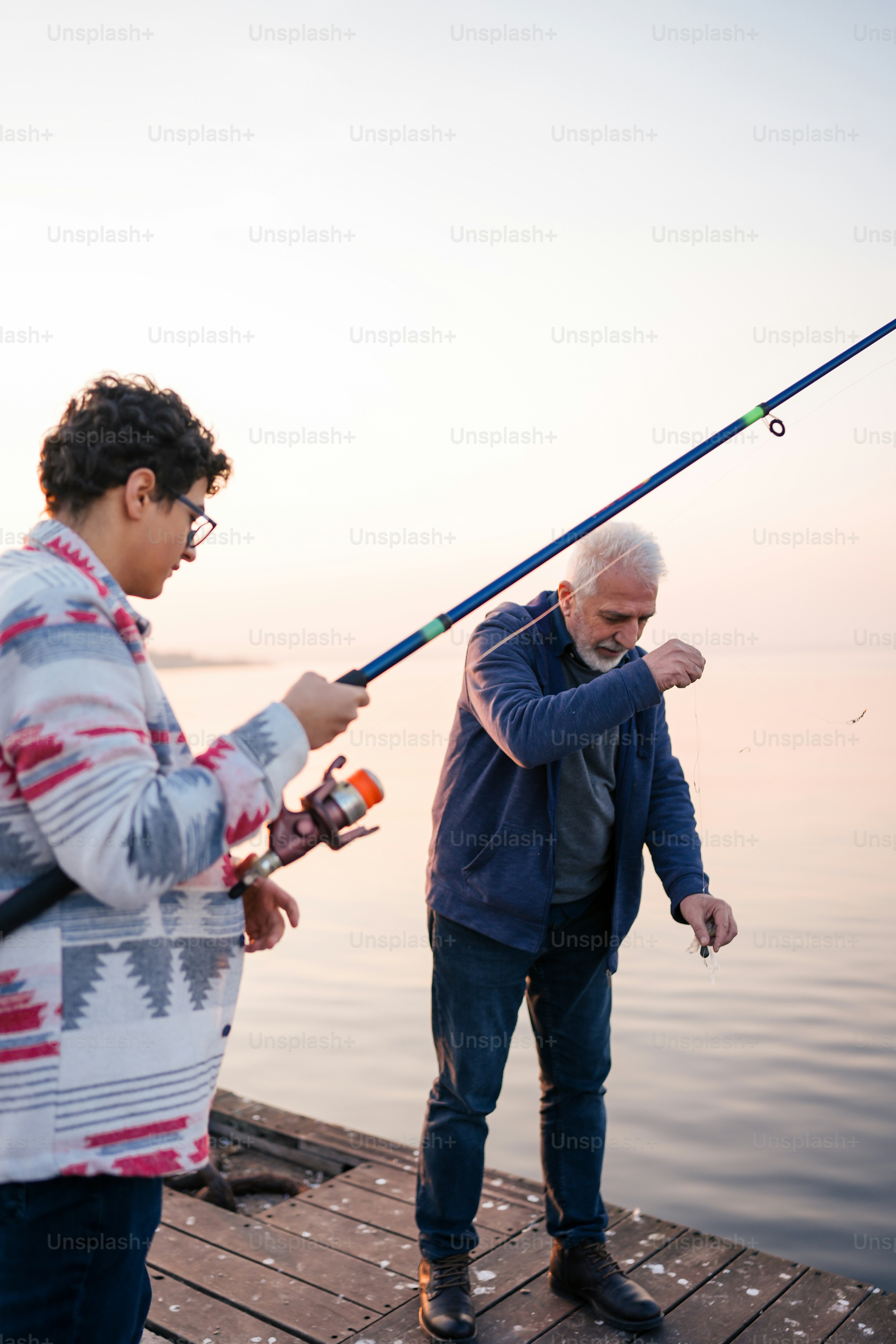 a man holding a fishing rod next to another man