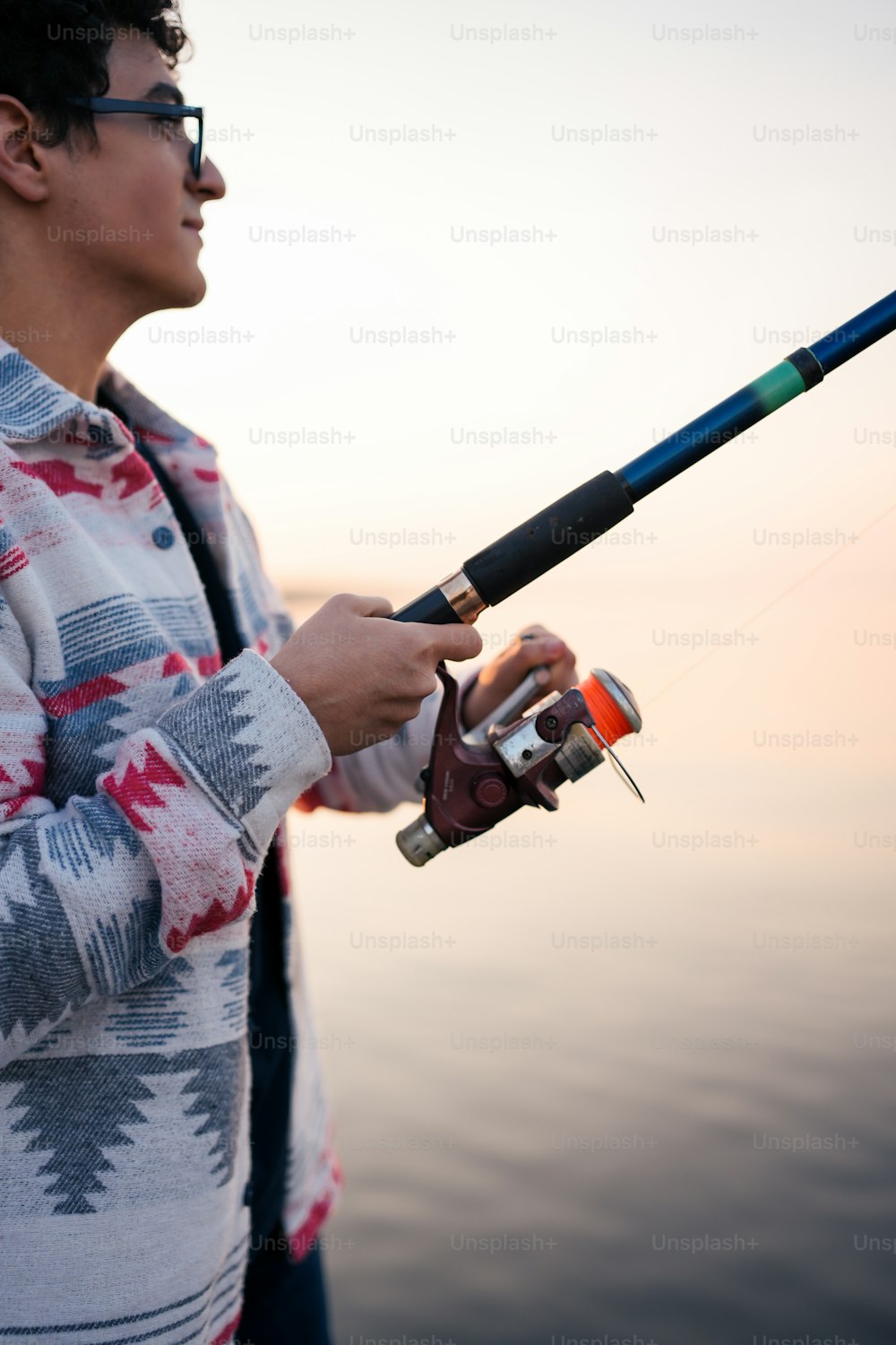 A man holding a fishing rod next to a body of water photo