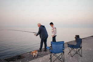 a man and a woman standing on a pier with a fishing rod
