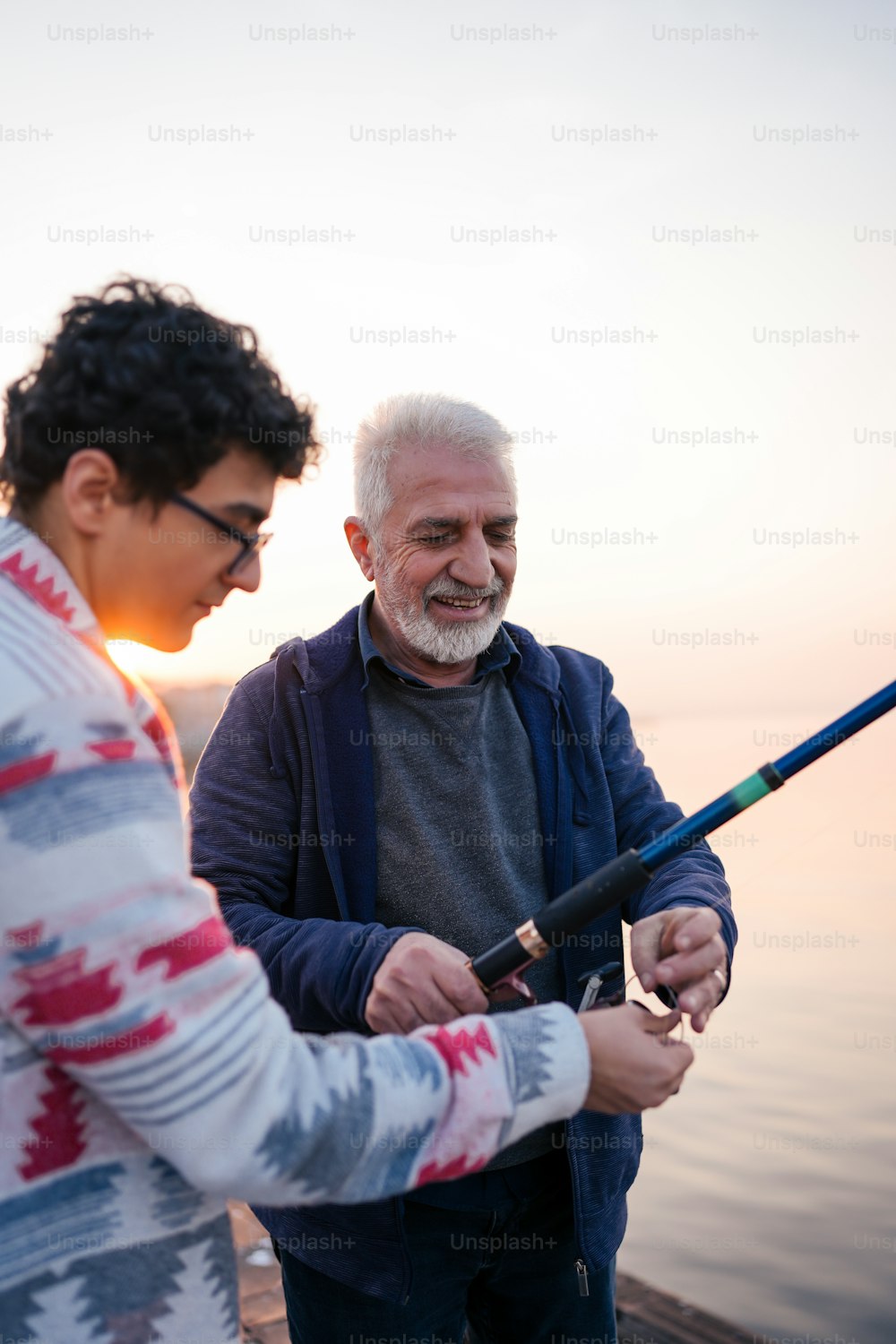 a man standing next to another man holding a fishing pole
