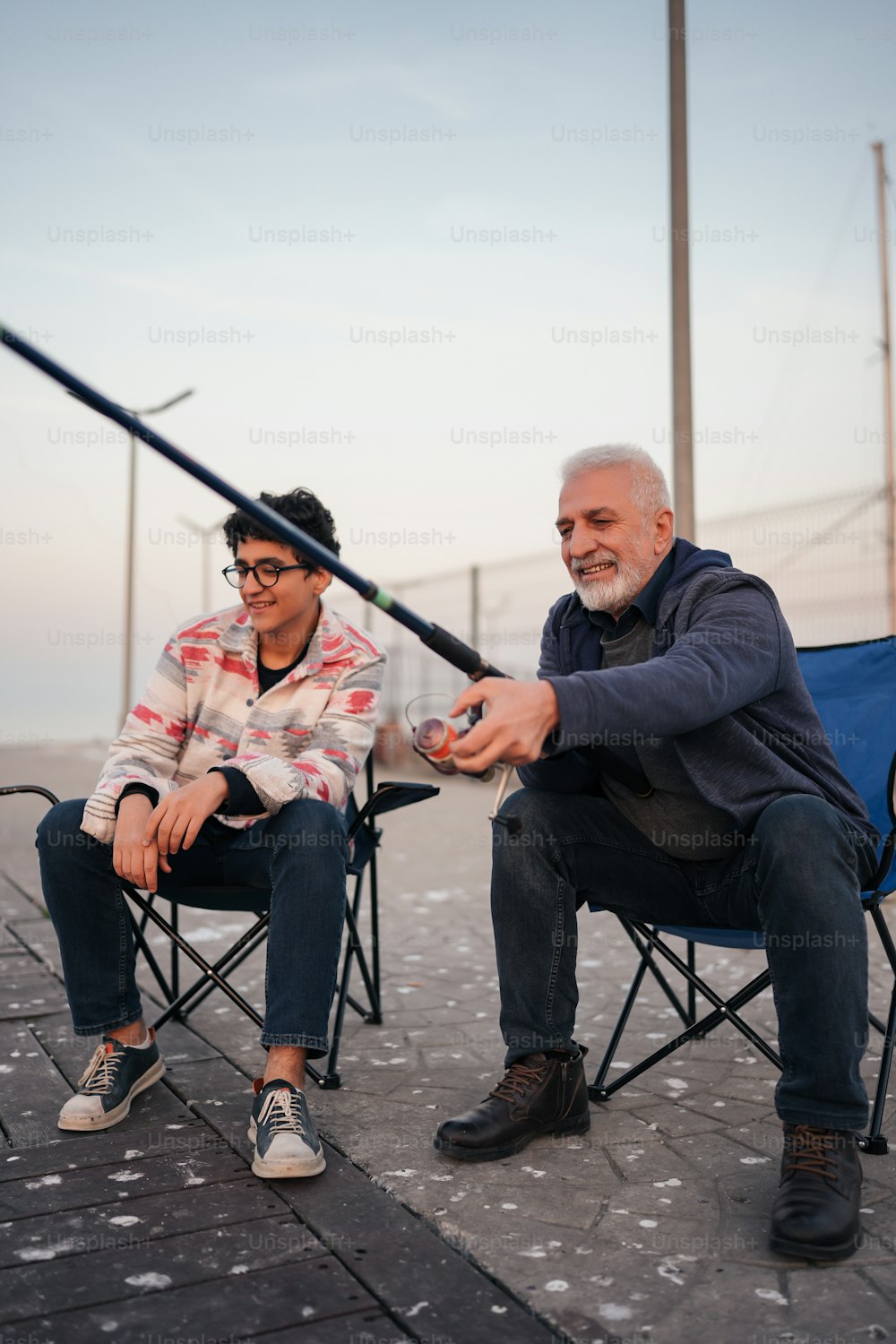 a man and a woman sitting in chairs with a fishing rod