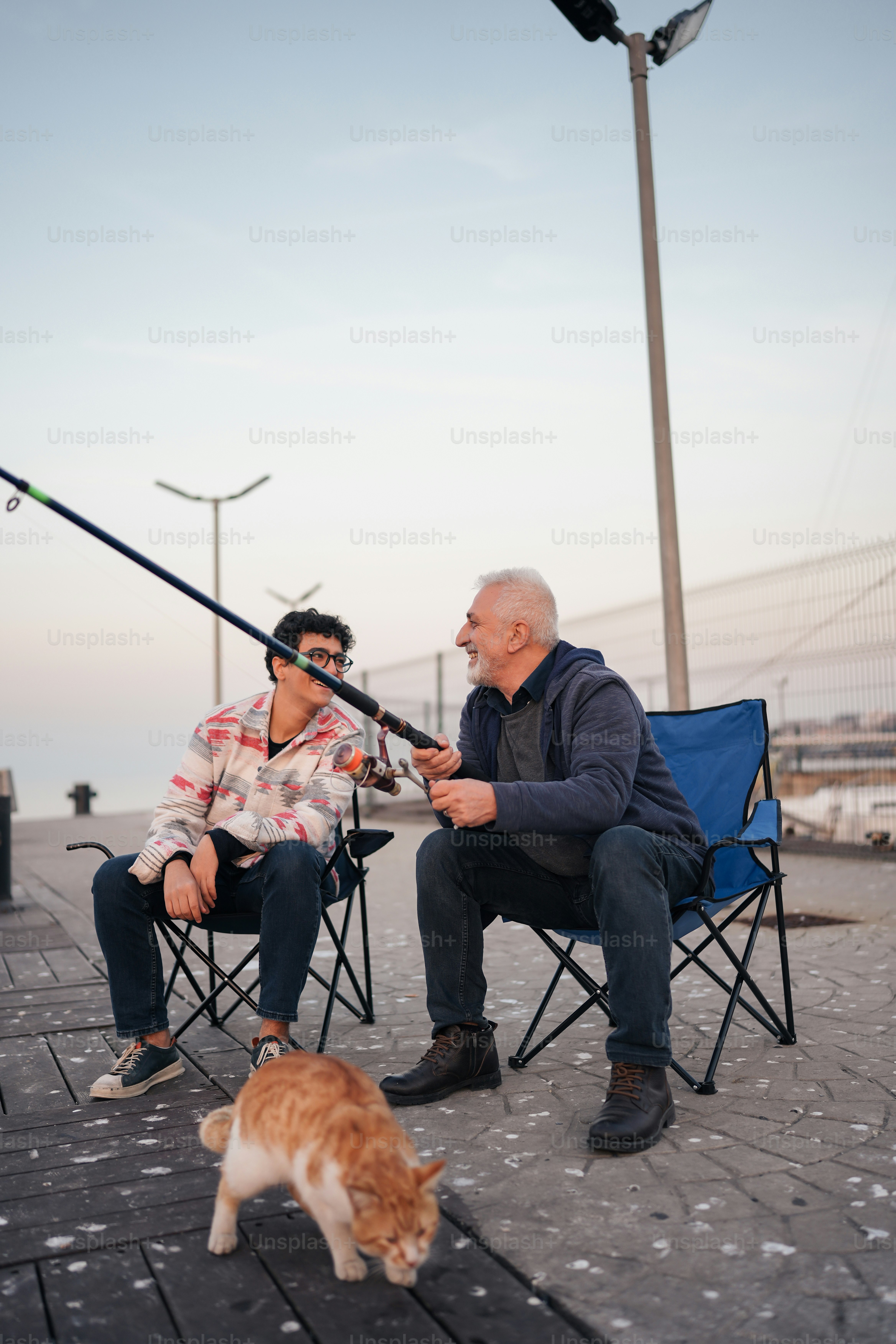 a couple of men sitting in lawn chairs next to a cat