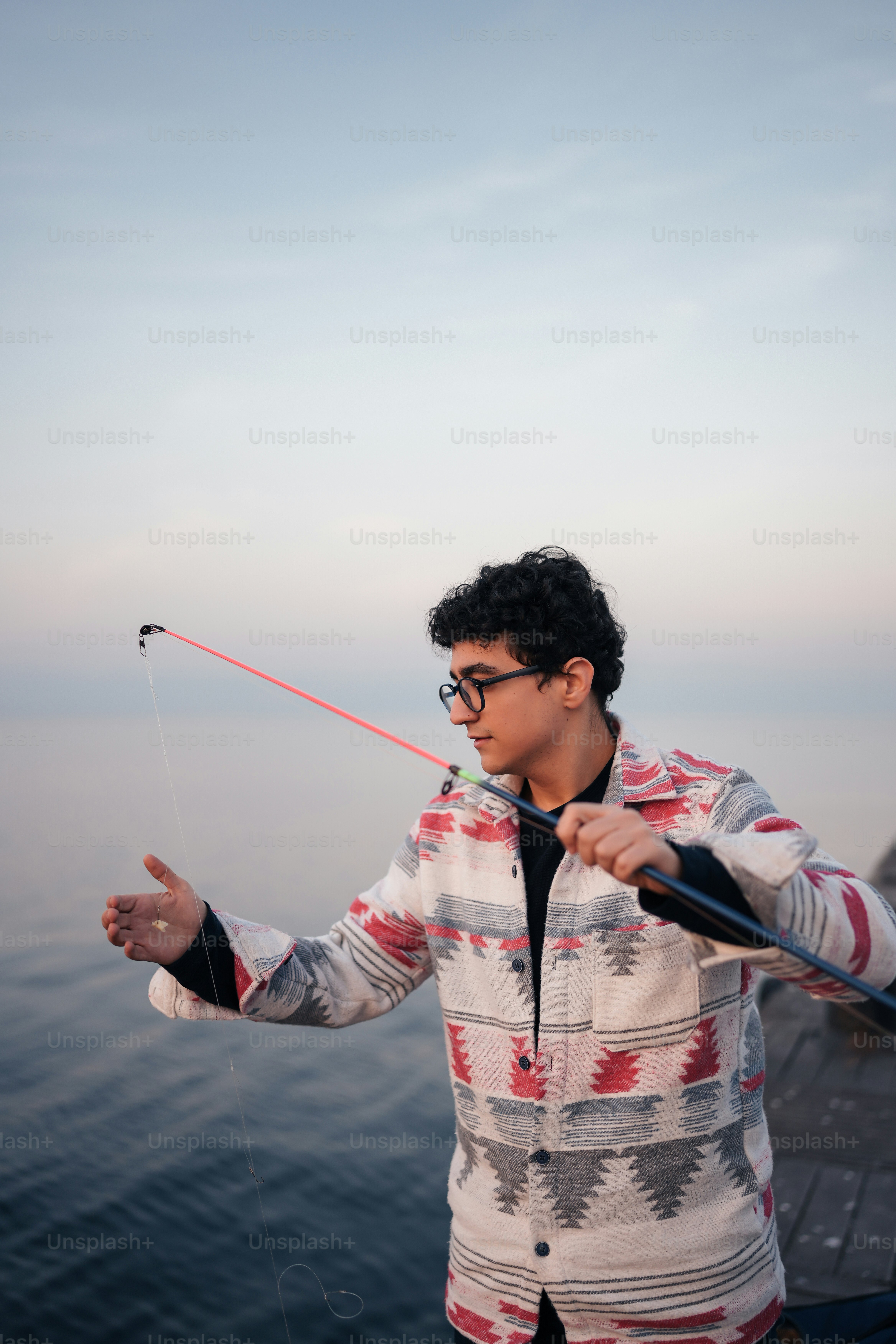 a young man holding a fishing rod on a boat
